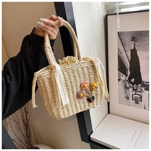 Détail du sac à main en paille tressée beige avec fleurs au crochet et ruban en dentelle