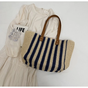 Close-up of woven straw tote bag texture with navy stripes and leather handles