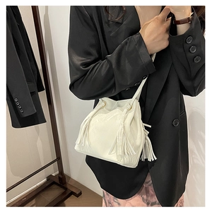 Détail d'un sac seau en cuir PU blanc avec de longues franges et détails dorés