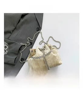 Detail of beige velvet bucket bag featuring sparkling rhinestone handle and chain strap