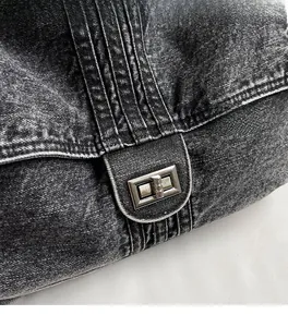 Close-up of washed denim crossbody bag featuring a rectangular metal twist-lock and stitching