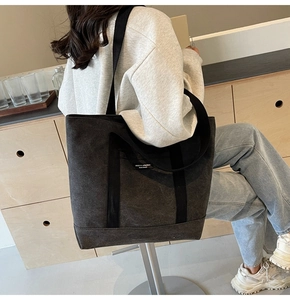 Detailed view of dark grey canvas tote bag with shoulder straps and woven brand label