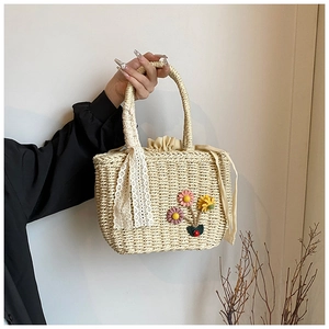 Détail du sac à main en paille beige tissé main avec fleurs 3D et ruban en dentelle