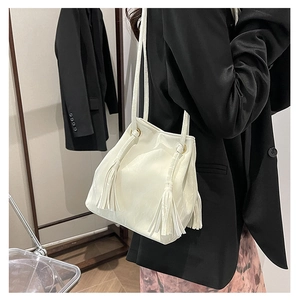 Détail du sac seau en PU blanc avec glands latéraux et finitions dorées brillantes
