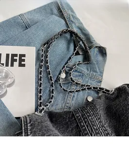 Close-up of black denim chain bag with frayed edges and silver hardware detail