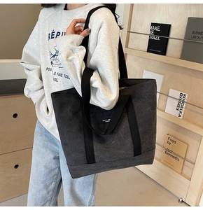 Detail of dark grey canvas tote bag featuring dual handles and woven logo patch