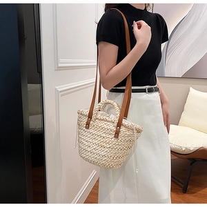 Detail of straw tote bag showing natural weave texture with brown leather straps