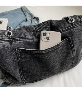 Detail of denim crossbody bag featuring a practical back pocket for smartphone storage