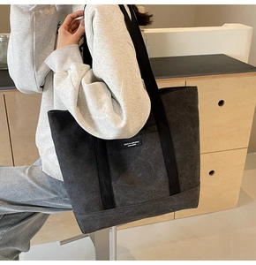 Close-up of charcoal grey canvas tote bag with long shoulder straps and brand label