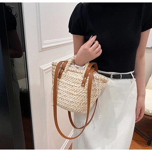 Straw tote bag detail with brown leather strap, rivet accents and drawstring lining