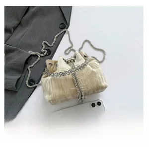 Detail of champagne velvet bucket bag with crystal leaf trim and silver chain strap
