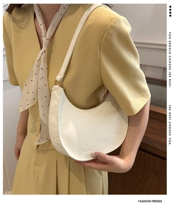 Close-up of white crescent moon hobo bag with glossy pleated texture on a model