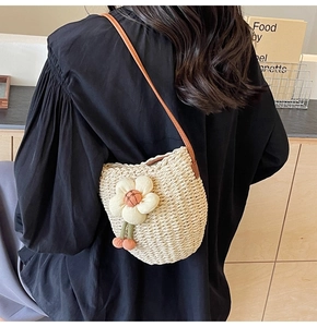 Close-up of woven bucket bag with 3D floral accent and brown leather shoulder strap