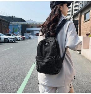 Close-up of black denim backpack with washed finish and metallic zipper detail