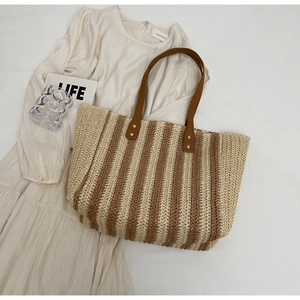 Detail of bohemian striped woven tote bag with brown leather handles and metal rivets