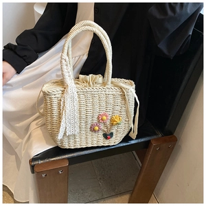 Détail d'un sac à main en paille tissé avec broderies florales et ruban de dentelle élégant