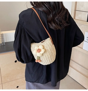 Close-up of handmade straw bucket bag with floral detail and brown leather strap