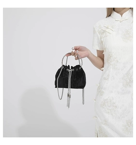 Detail of black velvet bucket bag with silver metal ring handle and fringe chains