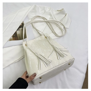 Sac seau minimaliste en similicuir brillant beige avec glands et clous dorés