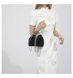 Detail of black velvet bucket bag with silver chain handle and metallic tassels