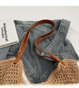 Detail of straw woven bag showing brown leather straps with gold metal rivets and lining