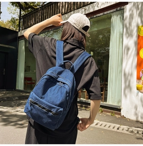 Detail of blue denim backpack showing comfortable wide shoulder straps and top handle design