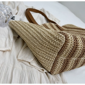 Detailed macro view of woven straw texture and premium brown leather straps of the tote bag