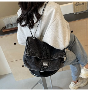 Close-up of washed denim shoulder bag with silver turn-lock and metal chain strap