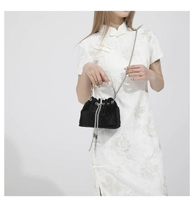 Detail of black velvet drawstring bucket bag with silver chain strap on white cheongsam