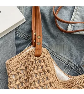Detailed close-up of woven straw bag with brown leather handles and metal rivet hardware