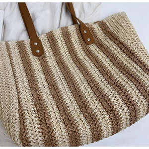 Detail shot of vintage woven straw tote bag texture with brown faux leather handles