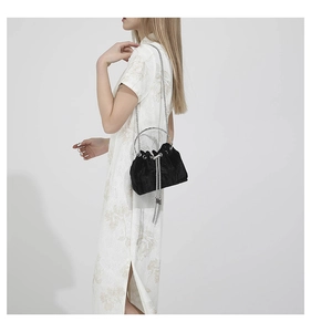 Detail of black velvet bucket bag with silver metal ring handle and chain strap