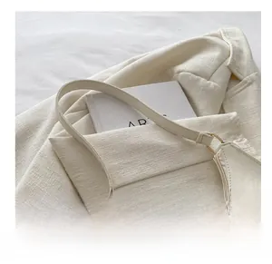 Detail of off-white PU leather hobo bag with sleek shoulder strap and minimalist texture