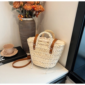 Minimalist straw woven handbag with brown leather handles and a secure drawstring liner
