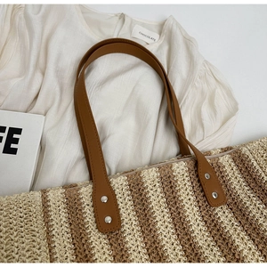 Detail of straw woven tote with striped pattern and premium leather handles