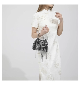 Close-up of black bucket bag featuring white floral embroidery and silver chain tassels