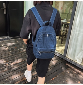 Detail of vintage denim backpack showing durable canvas texture and multi-layer zippers