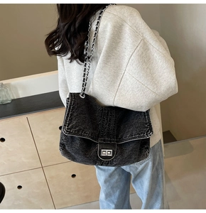 Detail view of black denim crossbody bag with silver twist lock and metal chain strap