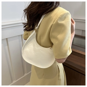 Detailed view of a white crescent moon bag with textured leather and gold hardware