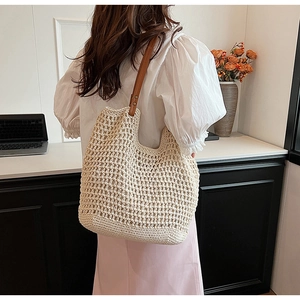 Detail showing handwoven texture and brown leather strap of large white straw tote bag