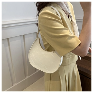 Detailed close-up of a cream crescent shoulder bag with marble texture on model