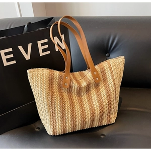 Detail of woven straw tote bag texture with brown faux leather straps and metal rivets