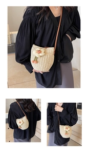 Detailed view of woven straw bucket bag with floral accents and cherry charms