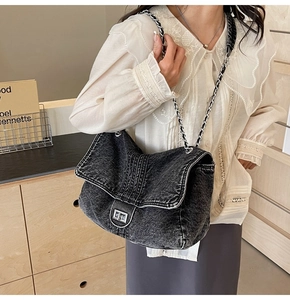 Close-up of black denim crossbody bag with silver twist lock and chain strap on a model