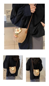 Close-up of handmade woven straw bucket bag with 3D floral petals and brown leather strap