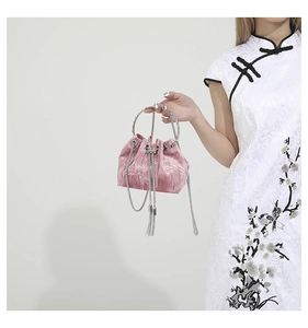 Detail of pink velvet drawstring bucket bag with silver chain handle and fringe tassel