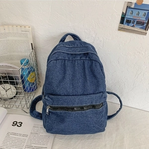 Minimalist vintage dark blue denim backpack with front pocket on white desk