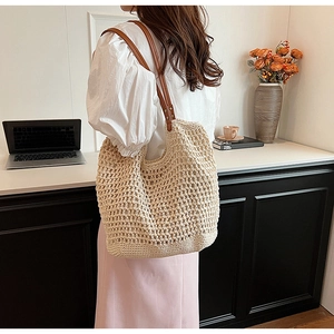 Detail of beige crochet tote bag with brown leather handles and metal rivet reinforcement