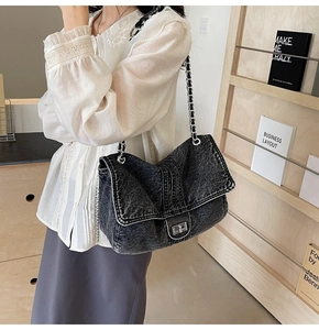Detail of vintage grey denim crossbody bag with metal twist lock and chain strap