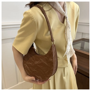 Detailed close-up of brown textured PU leather hobo bag on model with soft lighting